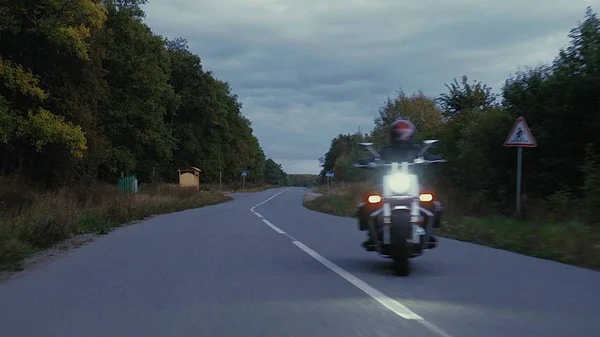 Een man rijdt een motorfiets een weg in bos — Stockfoto