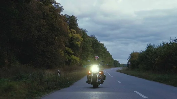 Seorang pria mengendarai sepeda motor menyusuri jalan di hutan — Stok Foto