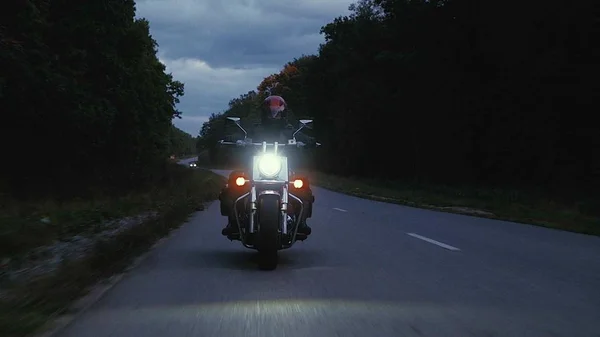 Человек едет на мотоцикле по дороге в лесу — стоковое фото