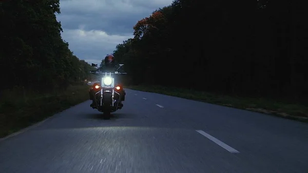 Um homem monta uma motocicleta por uma estrada na floresta — Fotografia de Stock
