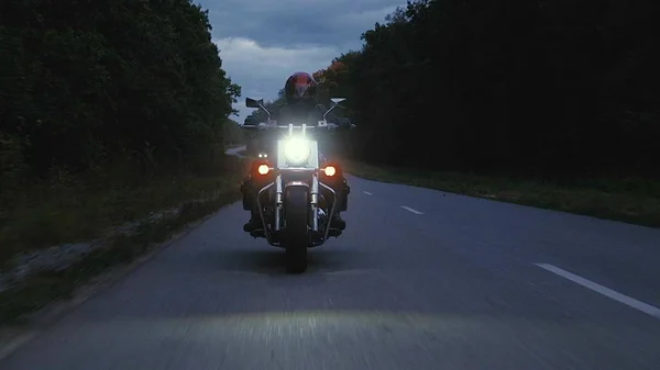 Een man rijdt een motorfiets een weg in bos — Stockfoto