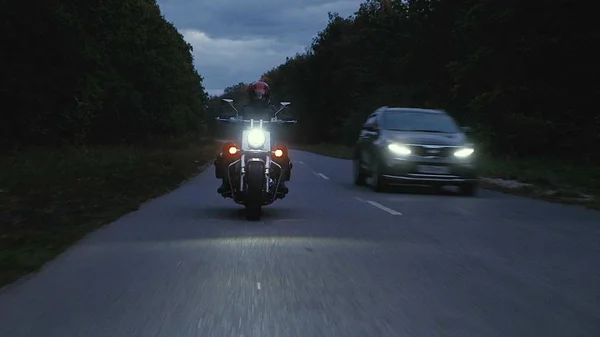 Человек едет на мотоцикле по дороге в лесу — стоковое фото