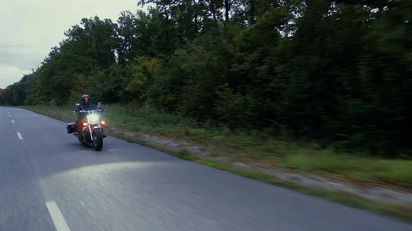 Un hombre conduce una motocicleta por un camino en el bosque —  Fotos de Stock