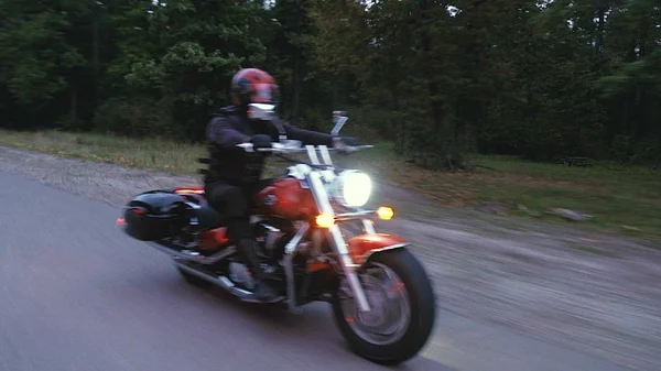 Bir adam bir motosiklet orman içinde bir yola rides — Stok fotoğraf