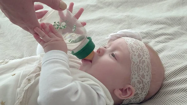 ボトルからミルクを飲みながら横になっている笑顔の赤ちゃん女の子 — ストック写真