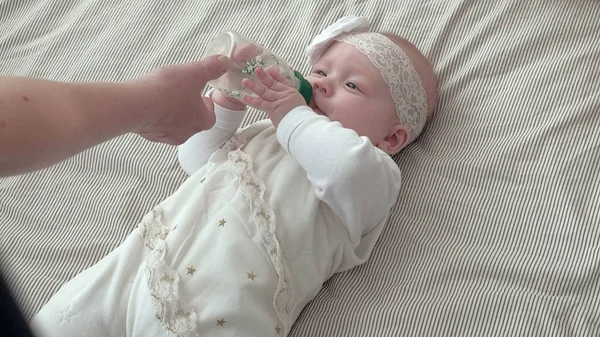 Niña sonriente acostada mientras bebe leche de un biberón — Foto de Stock