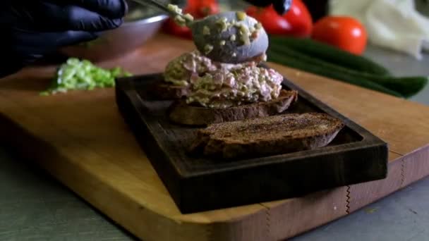 Hombre preparando bruschetta italiana con tomates al horno, albahaca y queso. Comida italiana cámara lenta — Vídeos de Stock