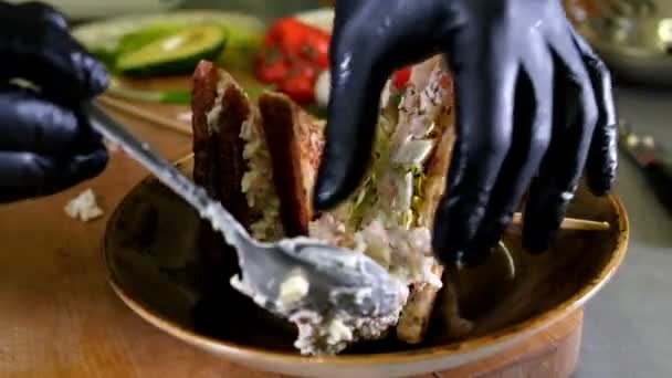 Ο άνθρωπος προετοιμάζει μεσημεριανό, σερβίρει σνακ Σάντουιτς ψημένο ψωμί πάνω σε ξύλο κοπής, με την πλευρά του πράσινη σαλάτα, υγιή εναλλακτική λύση για burgers και αργή moyion γράσο — Αρχείο Βίντεο