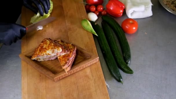 El hombre prepara el almuerzo, sirve bocadillo de pan a la parrilla en la parte superior de la tabla de cortar de madera, con lado de ensalada verde, alternativa saludable a las hamburguesas y grasa moyion lento — Vídeo de stock