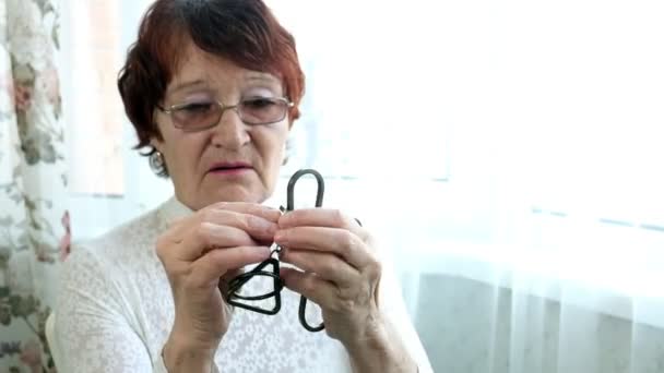 Une vieille femme démêle un puzzle en métal, entraîne l'activité cérébrale — Video