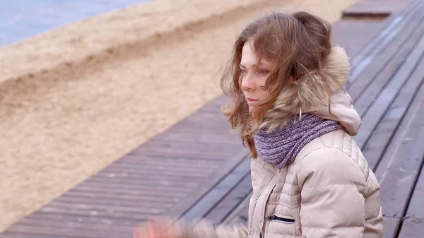 Romantica giovane donna che si rilassa sulla spiaggia con, bere tè caldo o caffè dal thermos. Serata tranquilla e accogliente . — Foto Stock