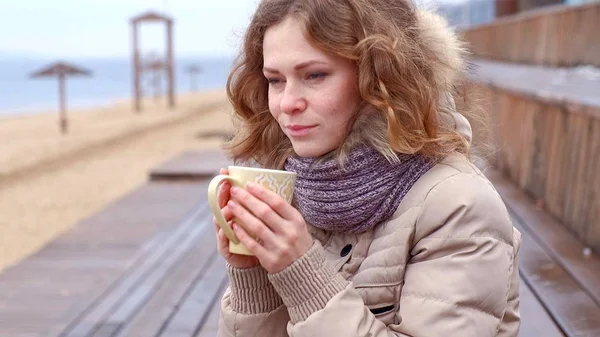 Romantique jeune femme se détendre sur la plage avec, boire du thé chaud ou du café de thermos. Soirée calme et confortable . — Photo