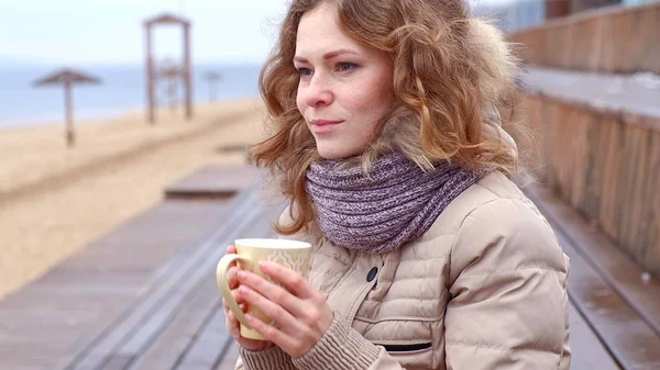 Romantique jeune femme se détendre sur la plage avec, boire du thé chaud ou du café de thermos. Soirée calme et confortable . — Photo