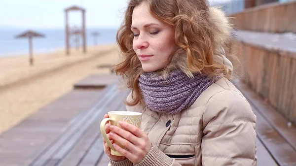 낭만적인 젊은 여자 휴식, 해변에 보온병에서 따뜻한 차 또는 커피를 마시는. 조용 하 고 아늑한 저녁. — 스톡 사진
