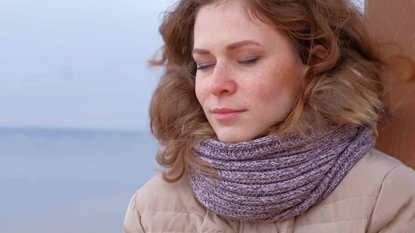 Romantische junge Frau, die es sich am Strand gemütlich macht, heißen Tee oder Kaffee aus der Thermoskanne trinkt. ruhiger und gemütlicher Abend. — Stockfoto