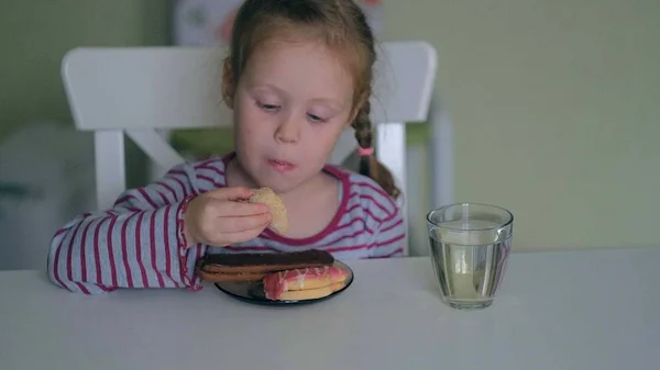 Een meisje eet aan de tafel thuis — Stockfoto