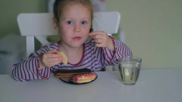 Een meisje eet aan de tafel thuis — Stockfoto