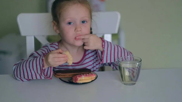 Een meisje eet aan de tafel thuis — Stockfoto