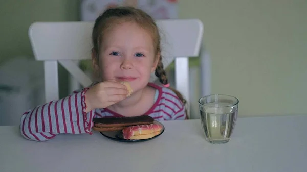 Een meisje eet aan de tafel thuis — Stockfoto