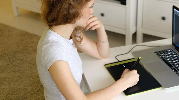 Kadın tasarımcı grafik tablet üzerinde çizer. Evde office içinde laptop ile çalışan kadın — Stok fotoğraf