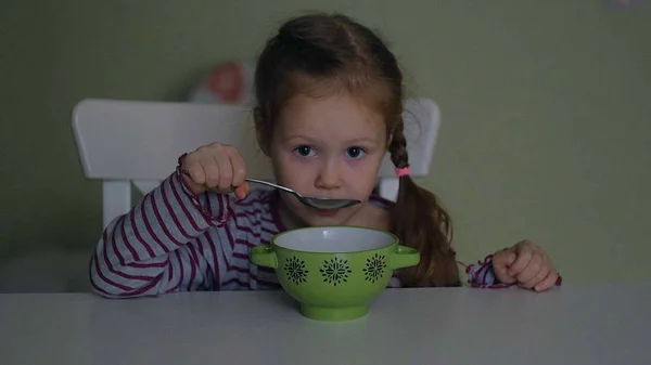 Een meisje eet aan de tafel thuis — Stockfoto