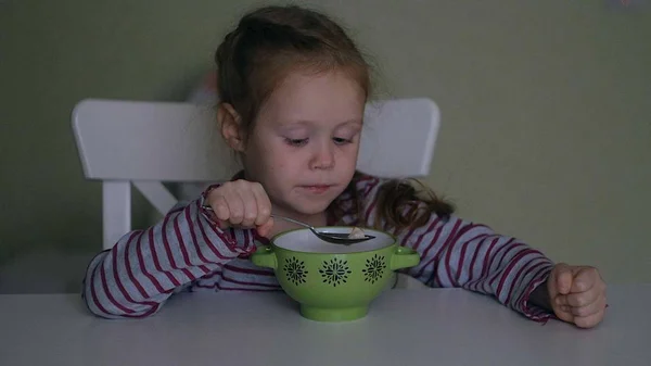 Uma menina come na mesa em casa — Fotografia de Stock