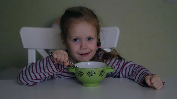 Een meisje eet aan de tafel thuis — Stockfoto