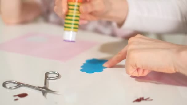 Жінка з дівчиною робить аплікацію кольорового паперу, сидячи за столом вдома — стокове відео