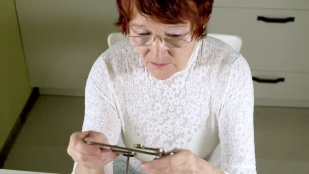 Eine alte Frau löst ein Metallpuzzle auf, trainiert Gehirnaktivität — Stockvideo