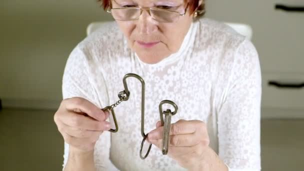 Uma velha desvenda um quebra-cabeça de metal, treina a atividade cerebral — Vídeo de Stock