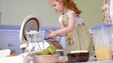 Genç mutlu anne ve onun sevimli kıvırcık yürümeye başlayan çocuk daughterr bir mutfak pişirmek