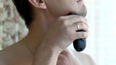 Adam tıraş sakal Elektrikli tıraş makinesi. Yanak üzerinde parmak swiping tıraş kontrol edin. Portre.