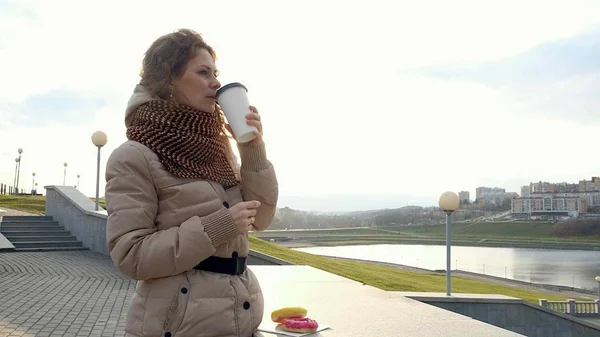 Beautiful young woman drinks coffee for a walk around the city — Stock Photo, Image