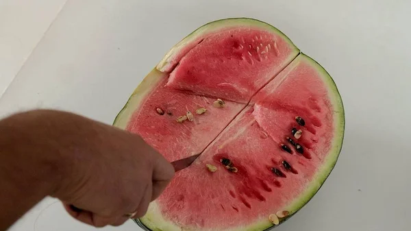 Mann schneidet Wassermelone mit Messer in Scheiben. — Stockfoto