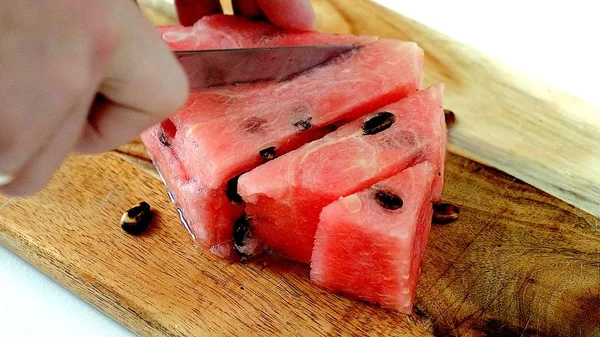 Mann schneidet Wassermelone mit Messer in Scheiben. — Stockfoto