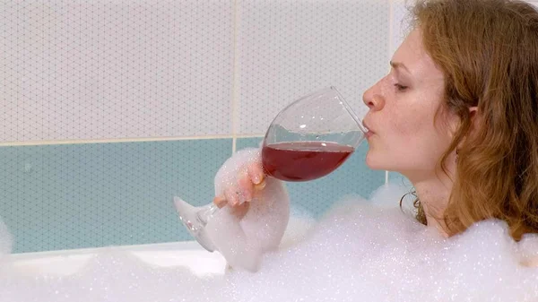 Woman blonde drinking wine while taking a bath. — Stock Photo, Image