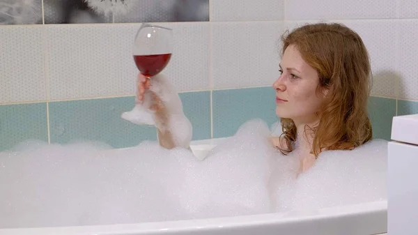 Femme blonde boire du vin tout en prenant un bain . — Photo