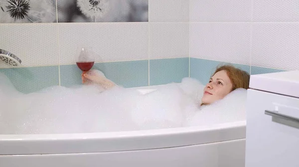 Femme blonde boire du vin tout en prenant un bain . — Photo