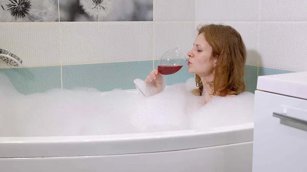 Mujer rubia bebiendo vino mientras toma un baño . —  Fotos de Stock