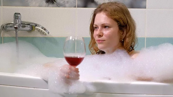 Женщина-блондинка пьет вино во время ванны . — стоковое фото