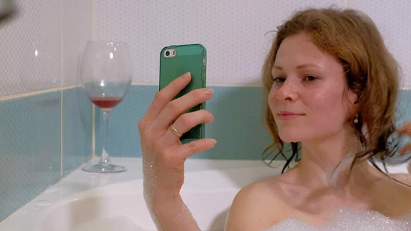 Femme blonde boire du vin tout en prenant un bain . — Photo