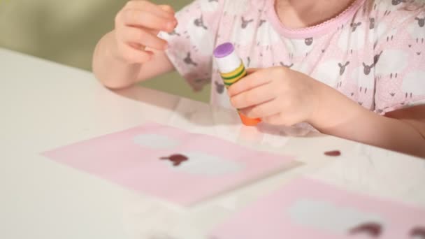 Una mujer con una chica haciendo una aplicación de papel de color sentada en una mesa en casa — Vídeos de Stock