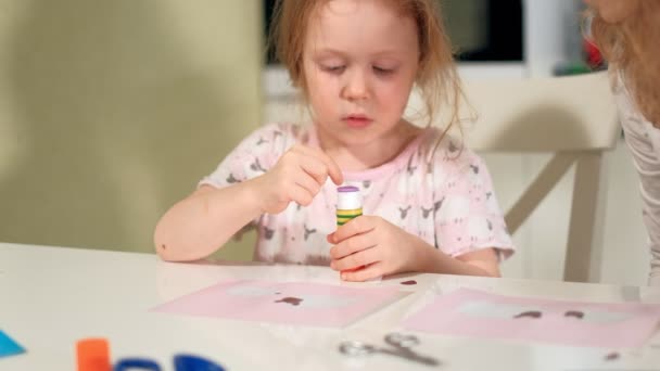 Egy nő, egy lány csinál egy alkalmazás, színes papír, ül egy asztalnál otthon — Stock videók
