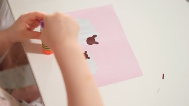 Eine Frau mit einem Mädchen bei einer Applikation von buntem Papier, die zu Hause an einem Tisch sitzt — Stockvideo