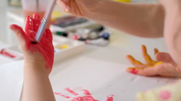 Familia feliz, madre e hija pequeña pintan con palmas en sus palmas — Vídeos de Stock