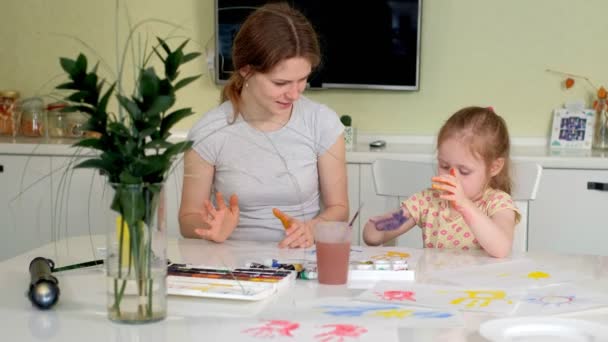 Счастливая семья, мать и маленькая дочь рисуют пальмами на ладонях — стоковое видео
