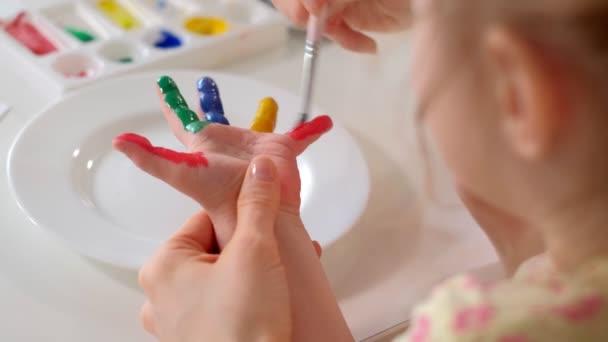 Glückliche Familie, Mutter und kleine Tochter malen mit Palmen auf ihren Handflächen — Stockvideo