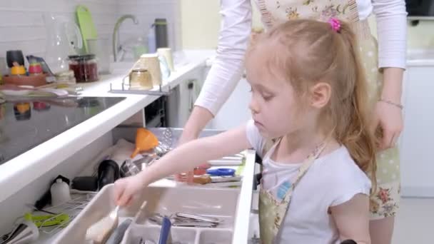 Дівчина допомагає моїй матері викласти посуд з посудомийної машини — стокове відео