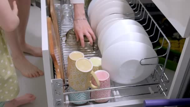 Девушка помогает моей маме выложить посуду из посудомоечной машины — стоковое видео