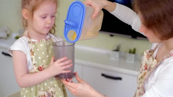 Joven madre feliz y su linda hija rizada en una cocina para cocinar — Vídeos de Stock